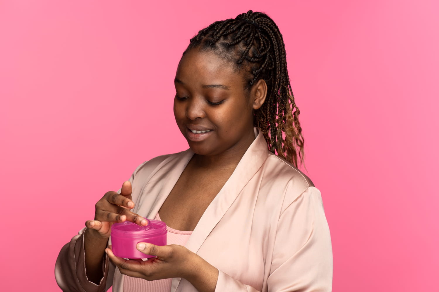 Black woman using moisturizer for soft, glowing skin.