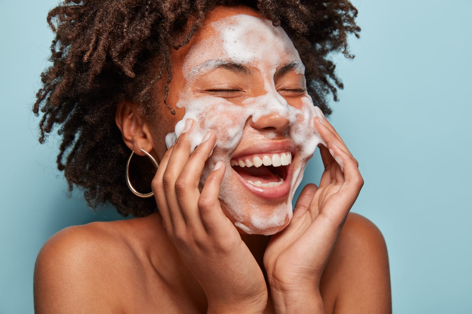 Black woman cleansing her skin to keep it fresh and healthy.