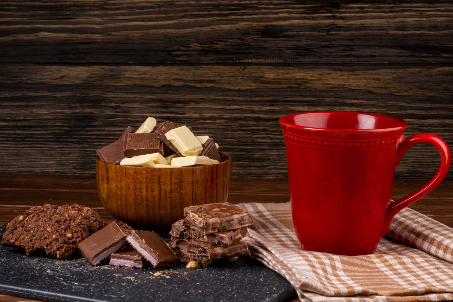 Dark chocolate squares on a rustic wooden table, showing rich cocoa texture.