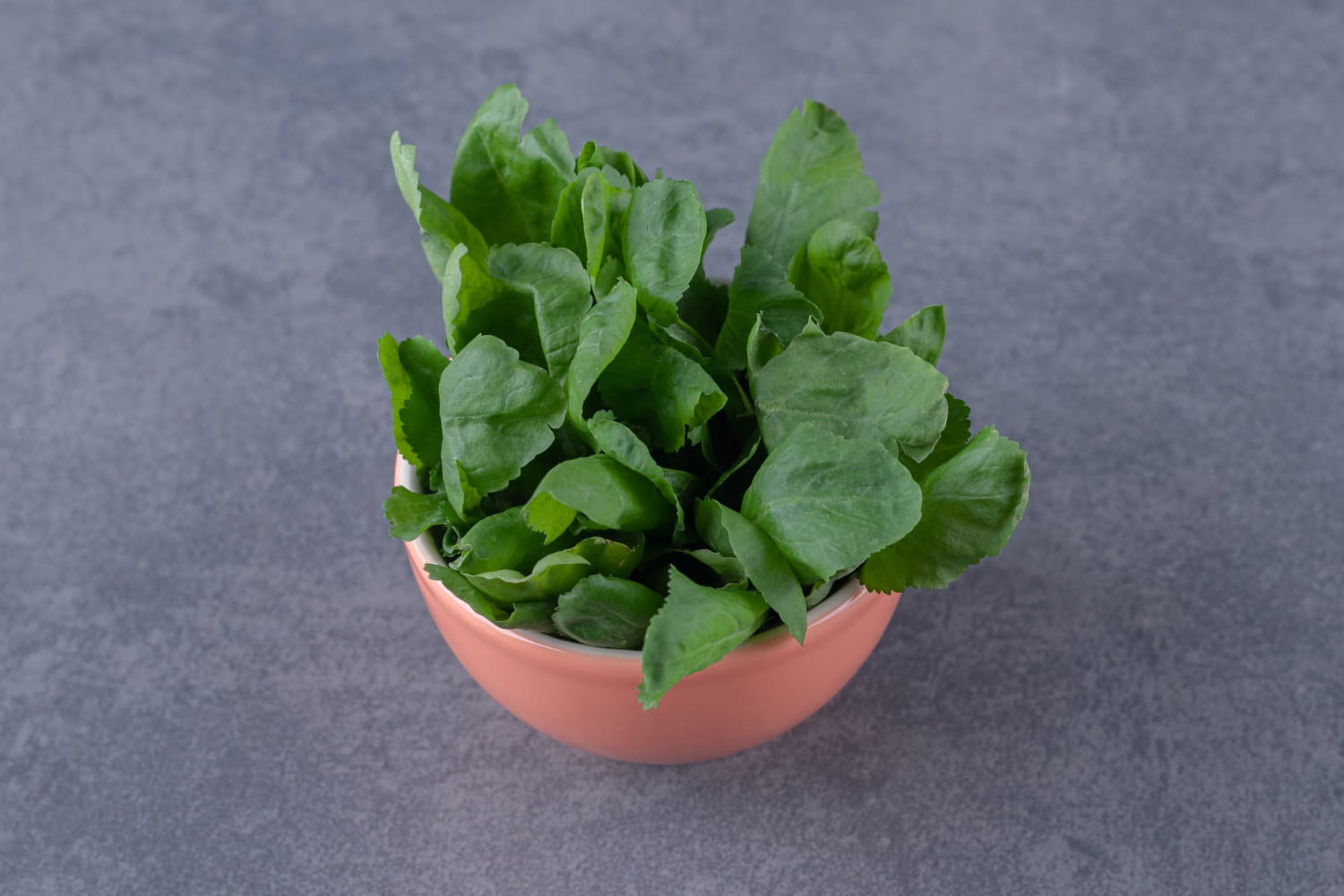 Fresh spinach leaves in a bowl, illustrating their vibrant green color.